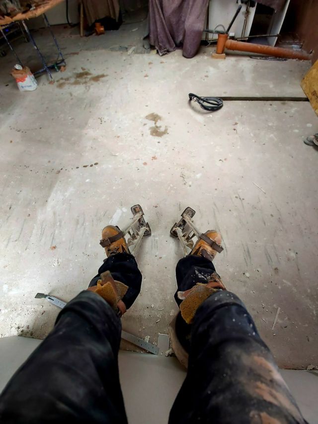 Plasterer wearing spiked screeding shoes standing on a freshly laid floor