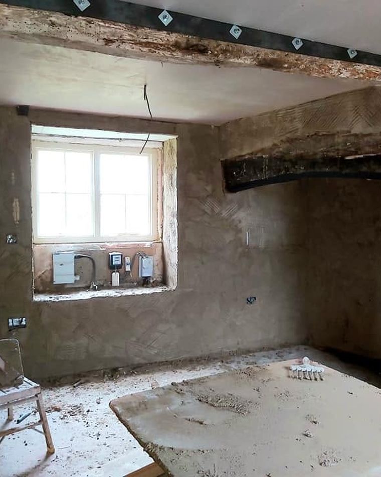 Scratch coat plaster applied in an old cottage room with an exposed beam